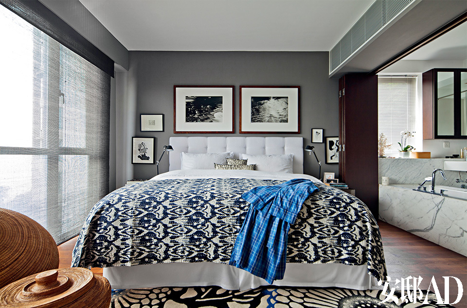 灰和蓝组成卧室中的主色彩，让室内与窗外的大海拥有同样深沉的气质。一扇屏风门区隔了主卧室和开放式的卫生间，让主人无论在哪儿都可以看到大海。带有日式花纹的蓝色Kawatori地毯由Boxer Rugs设计，床上蓝白相间的盖毯则是在印度斋普尔的收获。床头两侧各装有一具Tolomeo Micro的台灯，墙上悬挂着两幅由英国格拉斯哥艺术学校摄影系创始人Thomas Joshua Cooper拍摄的照片，近处的编织筐购自印度尼西亚龙目岛的市场。