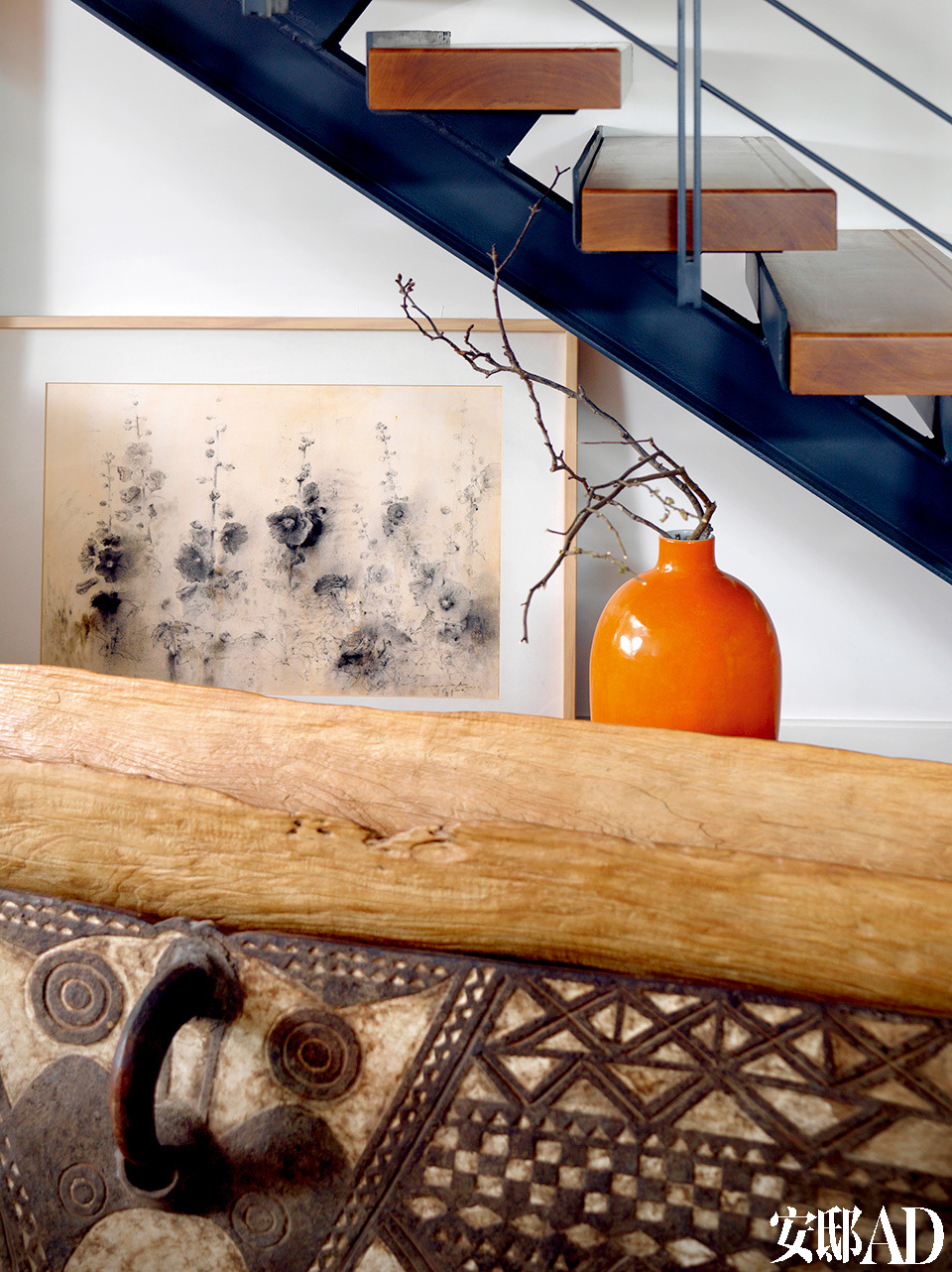 客厅一角处摆放着来自巴布亚新几内亚的独木舟和木刻面具。高瓷瓶是当代艺术品，背后的炭笔画是香港画家梁兆熙2010年的作品。
