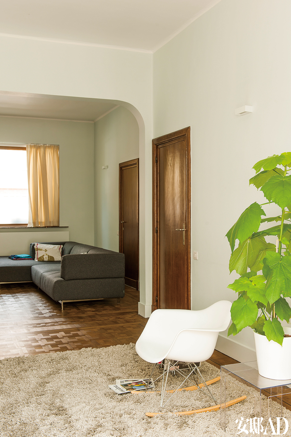 原有的玻璃门一直通向起居室。灰褐色地毯来自宜家家居，Eames白色摇椅和绿植增添了一份清新。