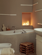 微弱而亲密的光线令浴室，有了温馨的氛围，浴缸一角的壁炉成了点睛之笔！大浴缸和盥洗盆来自品牌Flaminia，水龙头则来自Zazzeri。