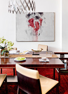 餐厅位于一层，吊灯是德国设计师Floyd Paxston的设计。墙上的油画来自台湾留英的新生代画家王姿婷，是2013年的作品。铜鸟臂环是非洲部落的艺术品，餐椅来自意大利品牌Poltrona Frau。镜头左手边的单椅是上世纪30年代老上海租界风格的椅子。波斯地毯来自阿富汗，是1980年的产品。