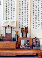 4层阁楼一角。台湾老家具都能上溯至清代。摆放书帖的架子是来自日本的古乐谱架，两个竹鸟笼都是清代的古董，木雕神像也是清代的作品。墙上挂的书法七条幅是台湾已故书法家杨绍印1983年的作品。