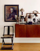 一层餐厅一边的柜子上摆放着来自非洲部落的木雕面具和铜马骑士。古董交椅是清代的老件。油画是台湾画家陈来兴1981年的作品，横幅水墨画则是北京水墨画家边平山1992年的作品。