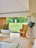 “ 艺术家之家”更像一个原始森林里温馨的小木屋。英国设计师Matthew Hilton的Irish橡木椅，右边为芭芭拉·赫普沃斯（BarbaraHepworth）的《Involute II》；左边黄铜装置同样是芭芭拉的作品《Three Forms》。这些艺术品想要让人过回简单古朴的自然生活。让艺术品更舒适地展现在一个“家”一样的空间里，告诉大家如何与艺术品共同生活，而不仅仅是站在那里静静地观赏而已。