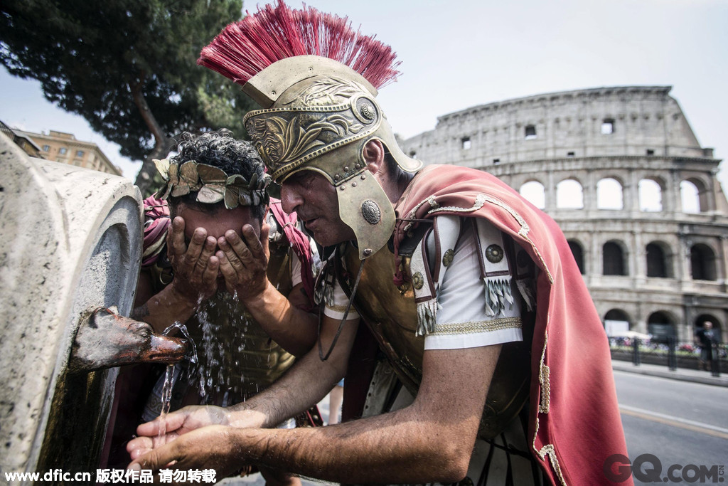 意大利罗马，两名扮成古罗马军团的男子接喷泉的水洗脸，降温解暑。 