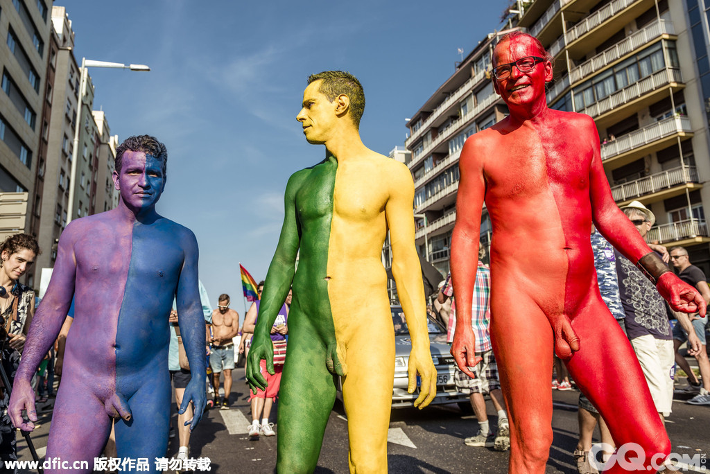 在西班牙巴塞罗那，三名男子大胆地在裸体上涂满颜料，拼起同志们的五彩旗。