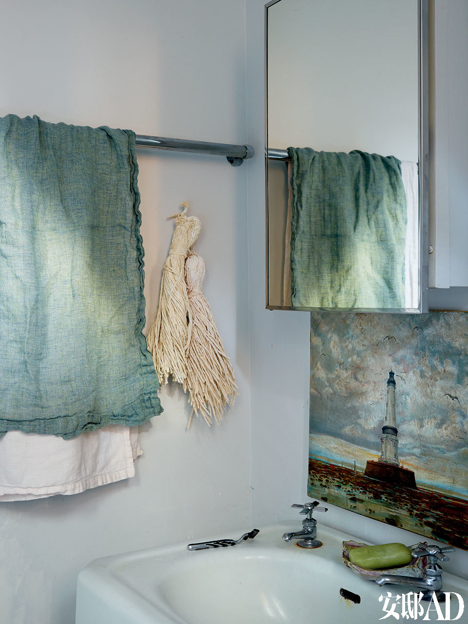 卫生间以青色为主基调，棉麻质地的毛巾、灯塔版画和淡绿色的肥皂让简约的角落更精致清爽。