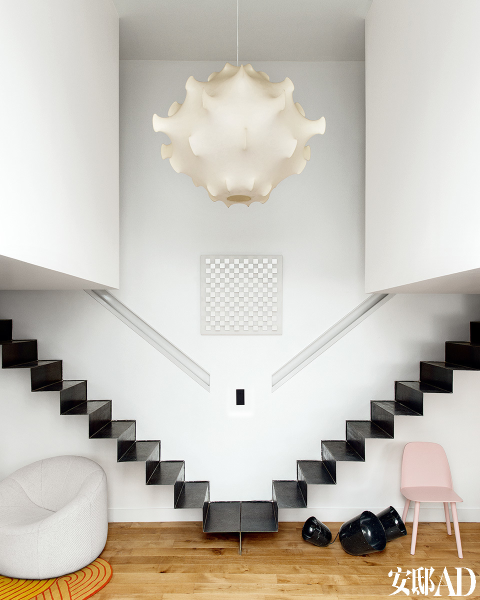 正厅中，在充当卧室的两个悬空“箱子”中间，天花板以下的空间被预留出来。出自Achille和Pier Giacomo Castiglioni的“Taraxacum S ”复古吊灯在那里熠熠生辉。地面上是A+A Cooren的“Orbit”灯具(来自Ymer & Malta工作室)和David Geckeler 设计的“Nerd”椅子(Muuto au Bon Marché)。墙上则挂着Marc Cavell的作品《Building》(来自88画廊)。