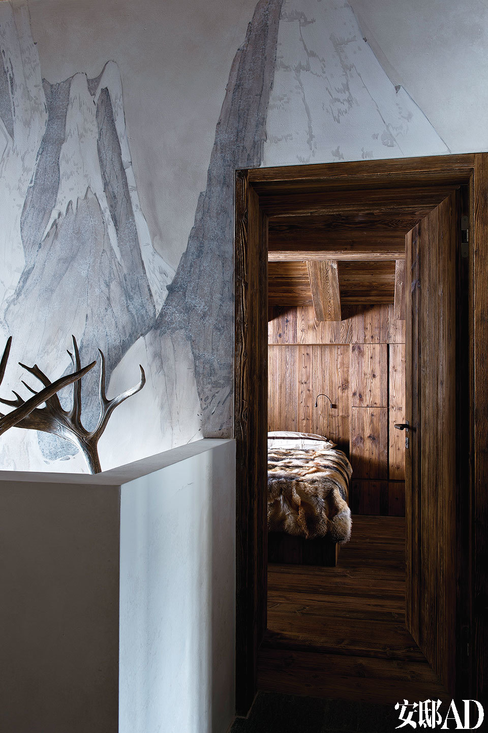 灰白色的墙壁，搭配卧室的木头质地，一截露出的鹿角衬着，最适合做一段山中美梦。