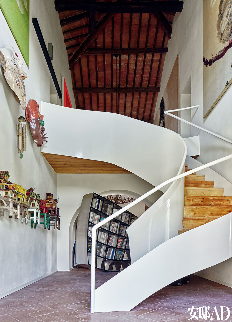 楼梯由MdAA建筑工作室设计。左侧墙壁上的艺术作品被分成三行挂设，这加强了家里这部分空间的双重高度感。从下往上，最近的是
中国艺术家陈箴2000年用蜡烛制作的作品Un Village sans frontières； 第二行是Luigi Ontani
（1998/2009）的作品Máscaras Musicales《音乐面具》，第三行的绿色图画Whiring Green是意大
利艺术家Aldo Mondino 1997年的作品。楼梯右侧的墙壁上挂着Julian Schnabel的画作。照片
的尽头，楼梯的后方是Ron Arad在2007年设计的书架“Restless”。
