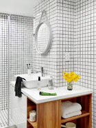 浴室位于卧室与客厅之间，呈长条状。只用最简单的10cm x 10cm的白色瓷砖贴满四面，却显得简洁爽利，颇有极简风姿。墙上的镜子来自Vitra，是HAY Studio在2003年推出的作品。