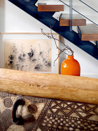 客厅一角处摆放着来自巴布亚新几内亚的独木舟和木刻面具。高瓷瓶是当代艺术品，背后的炭笔画是香港画家梁兆熙2010年的作品。
