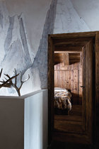 灰白色的墙壁，搭配卧室的木头质地，一截露出的鹿角衬着，最适合做一段山中美梦。