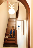 新装的楼梯采用了木质材料，与各个房间里的木地板相呼应，带来温暖的质感。坐在楼梯上的，是Kris夫妇俩8岁的儿子Edgar，远处厨房里的小女孩儿， 则是比Edgar小两岁的妹妹Julia。